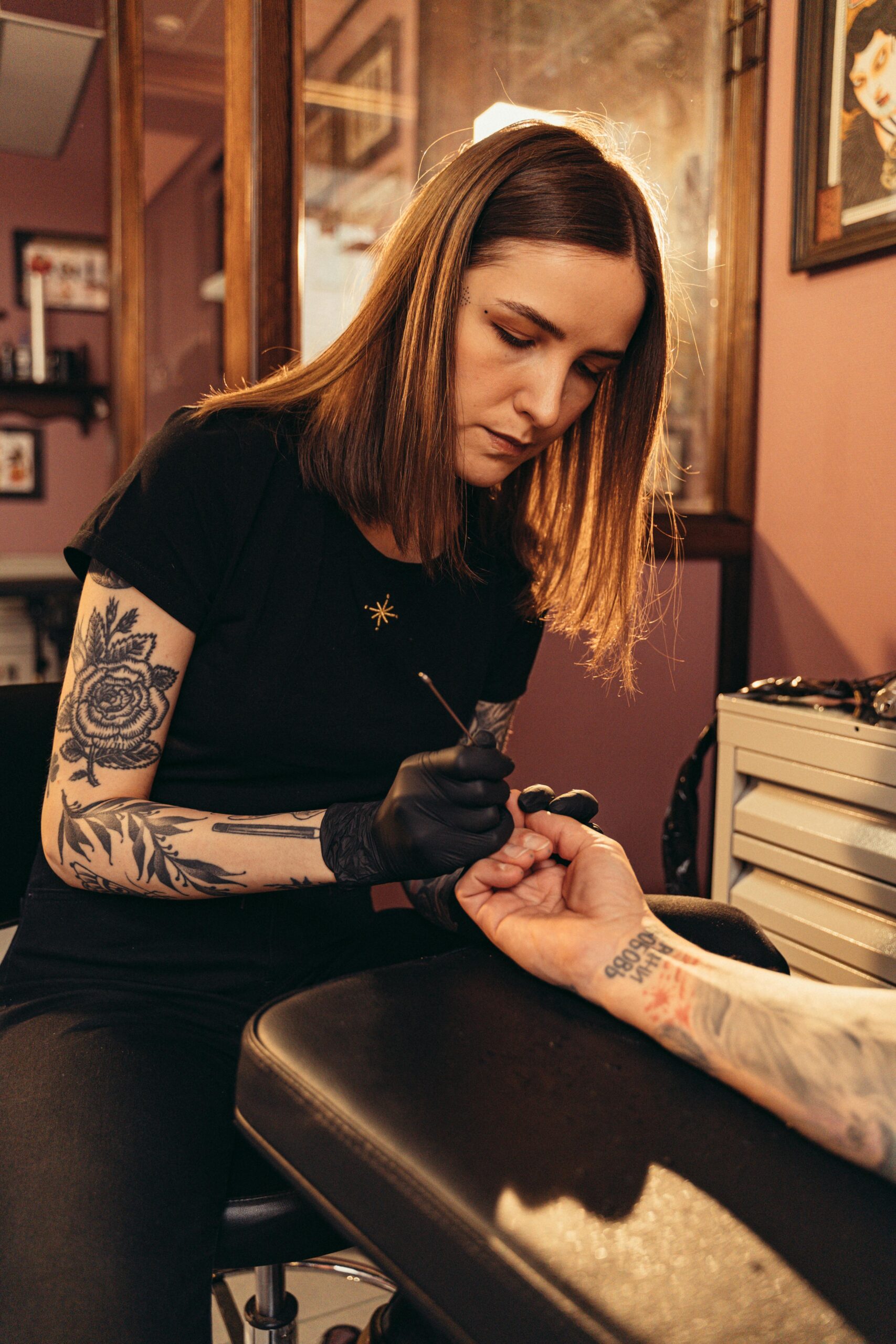Tattoo artist at work in a studio, creating intricate designs on a client's hand.